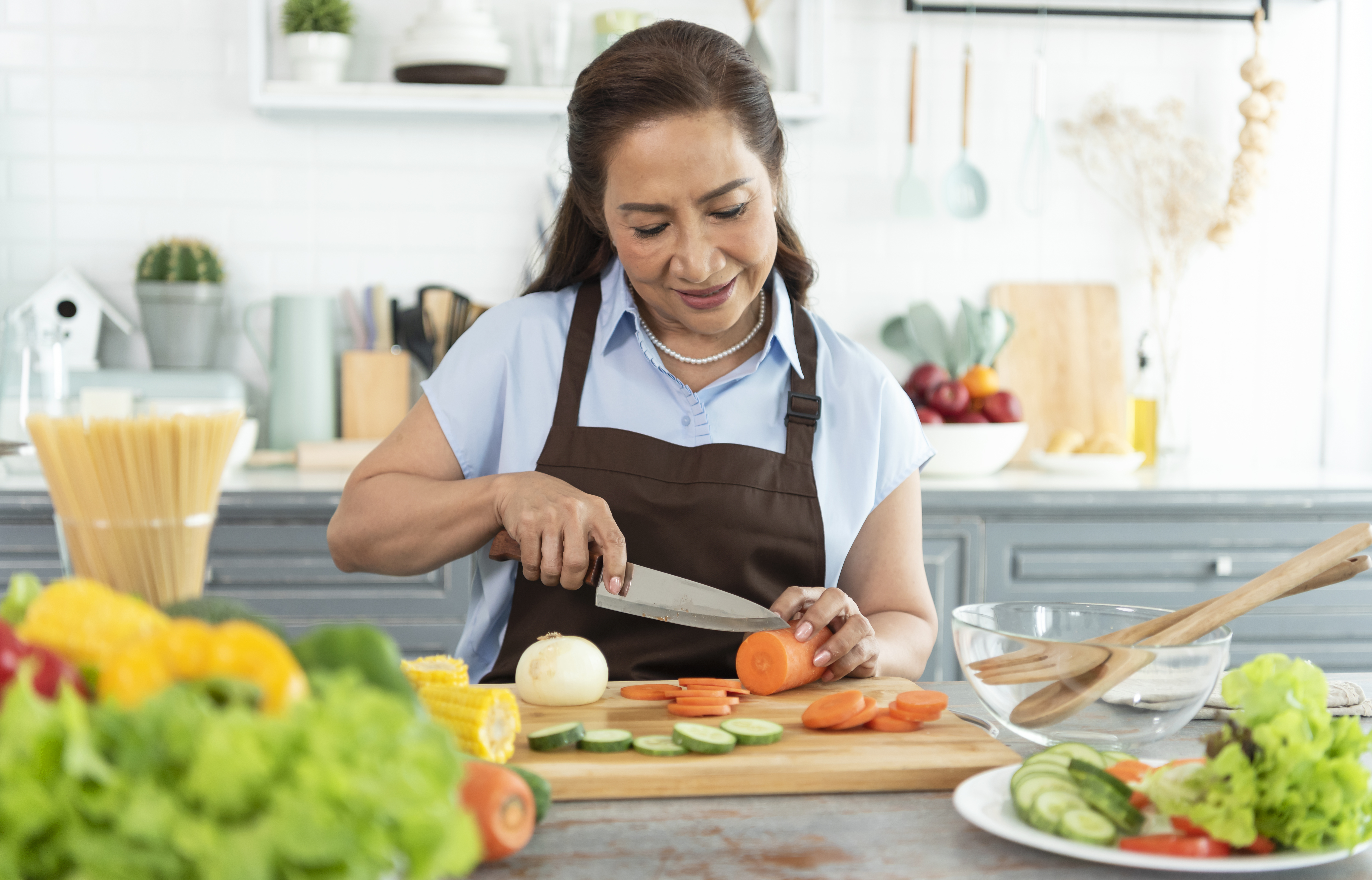 https://img.moneyduck.com/article_attachment/1664875378-happy-smiling-asian-older-woman-apron-cut-vegetables-while-cooking-salad-kitchen.jpg