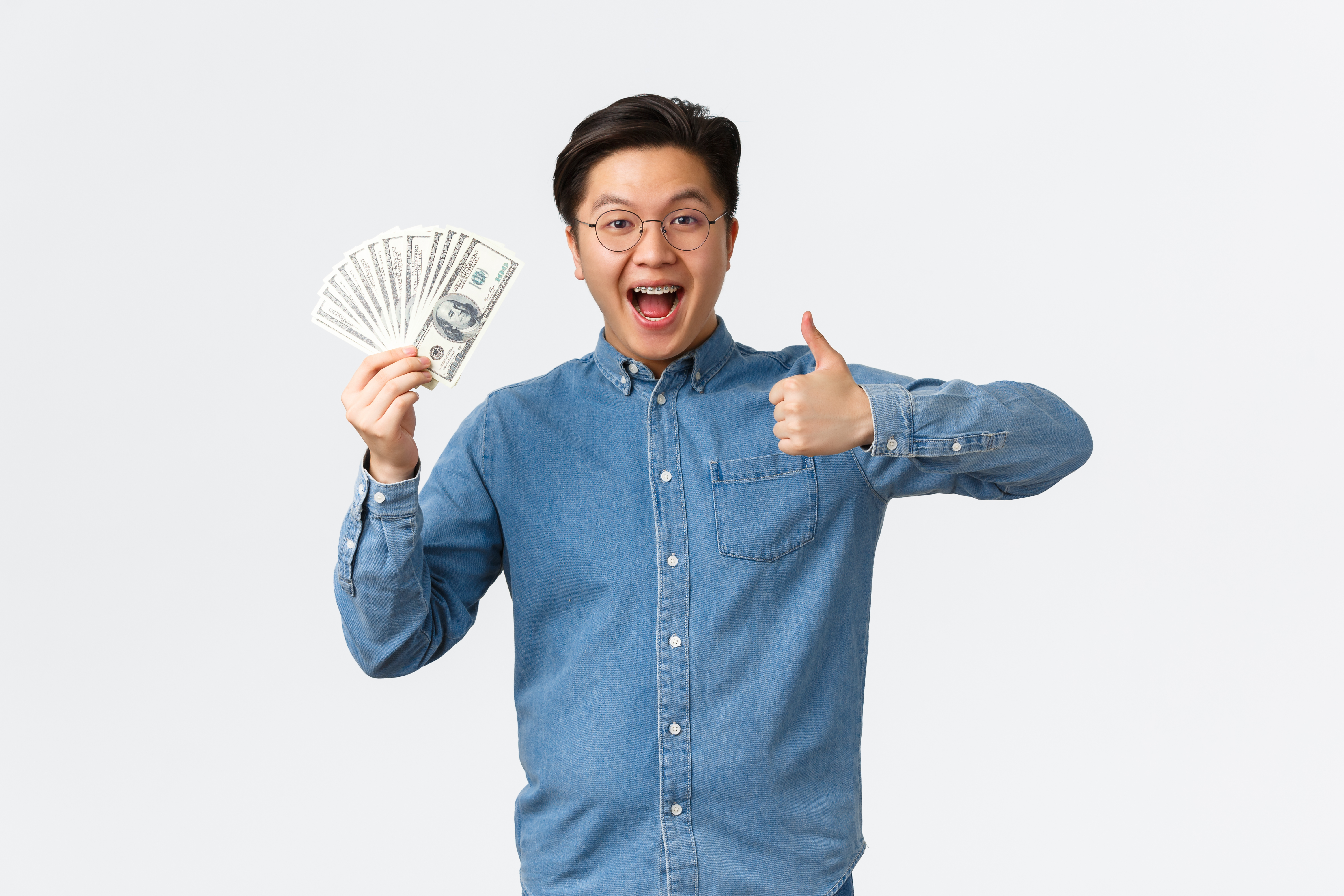 https://img.moneyduck.com/article_attachment/1669106601-excited-smiling-asian-man-with-braces-glasses-showing-thumbsup-waving-money-receive-paycheck.jpg