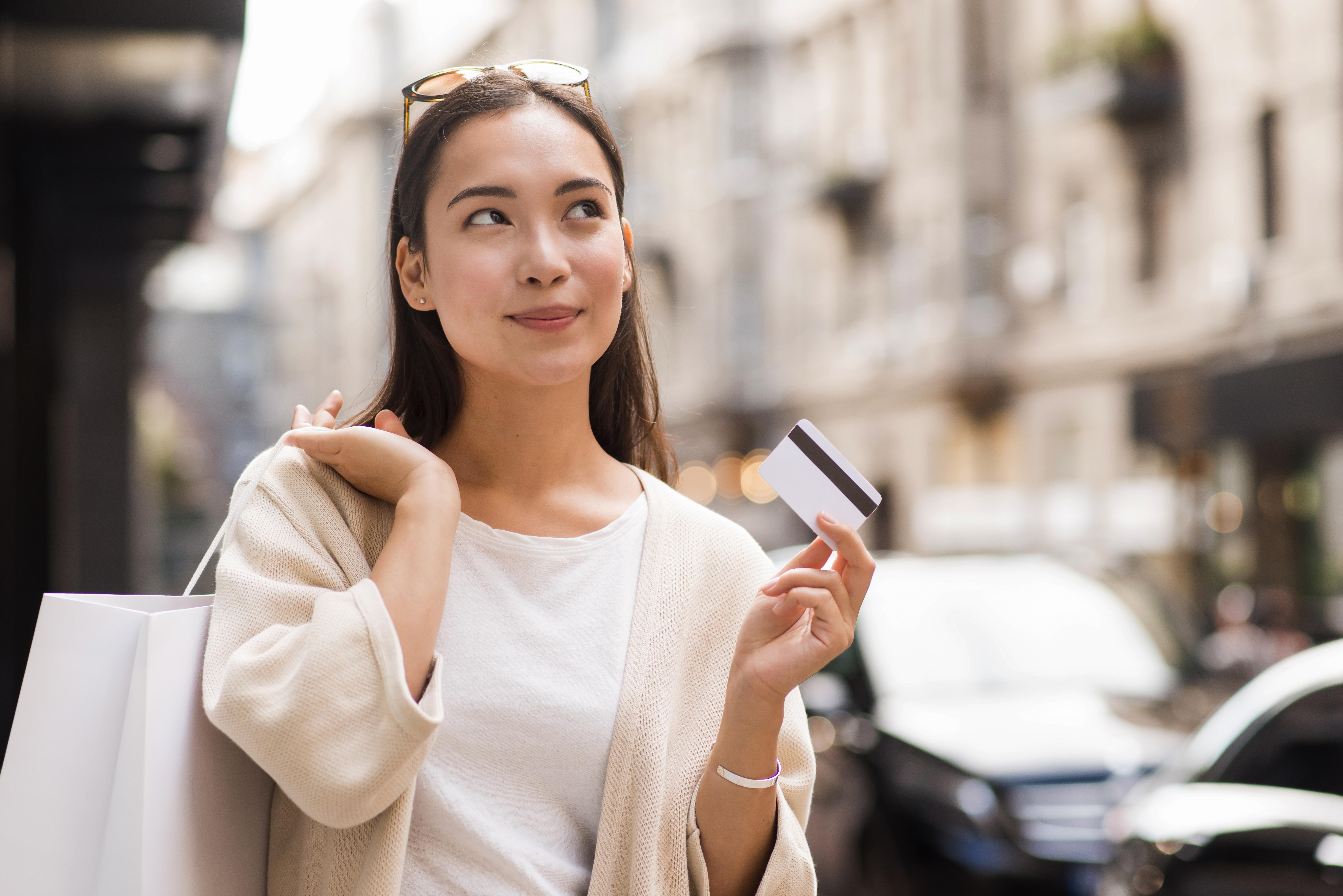 https://img.moneyduck.com/article_attachment/1670314085-woman-outdoors-holding-credit-card-shopping-bag.jpg