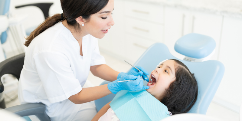 Dokter gigi sedang memeriksa pasien anak