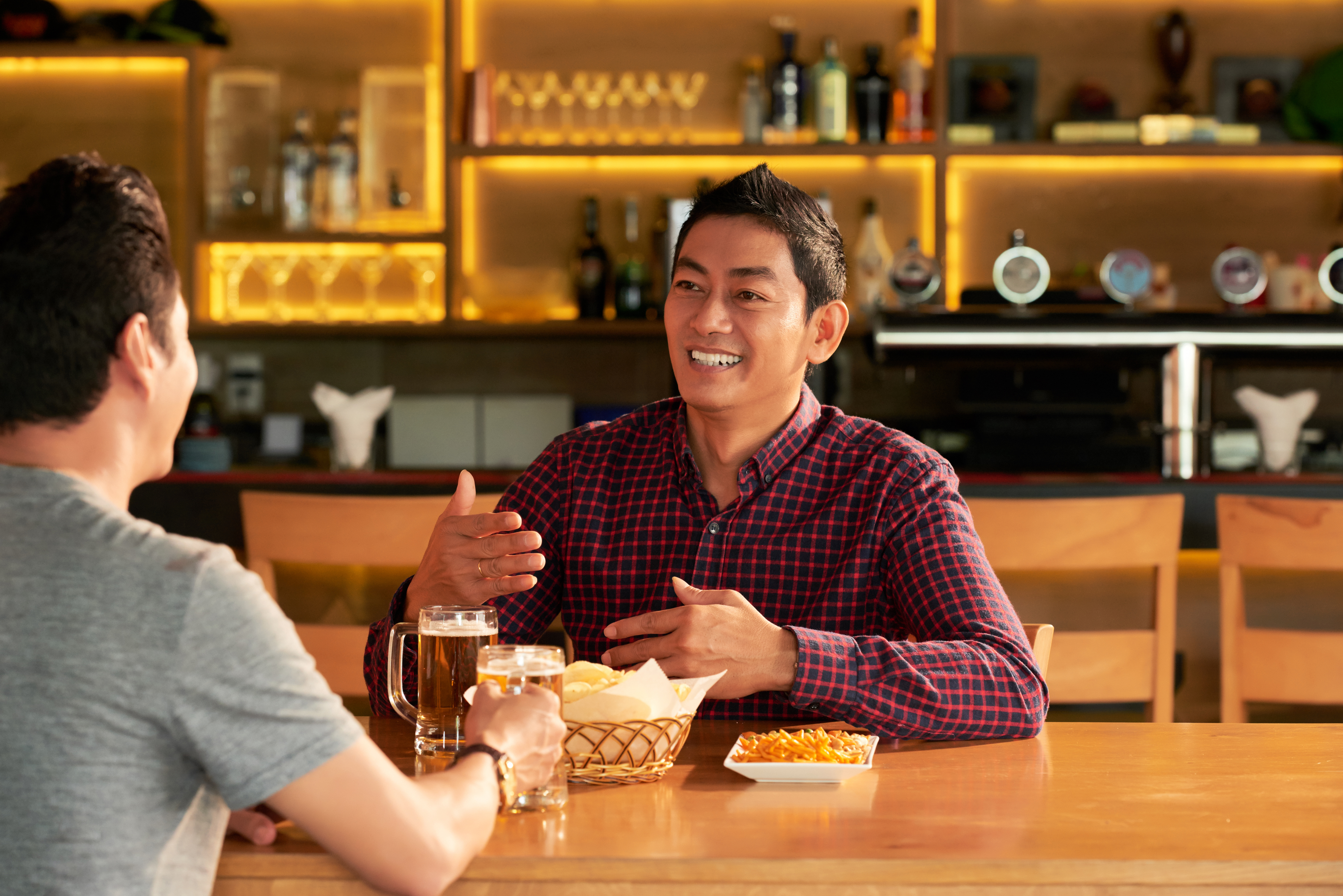 https://img.moneyduck.com/article_attachment/1677816793-two-asian-male-friends-sitting-table-bar-with-mugs-beer-snacks-chatting.jpg